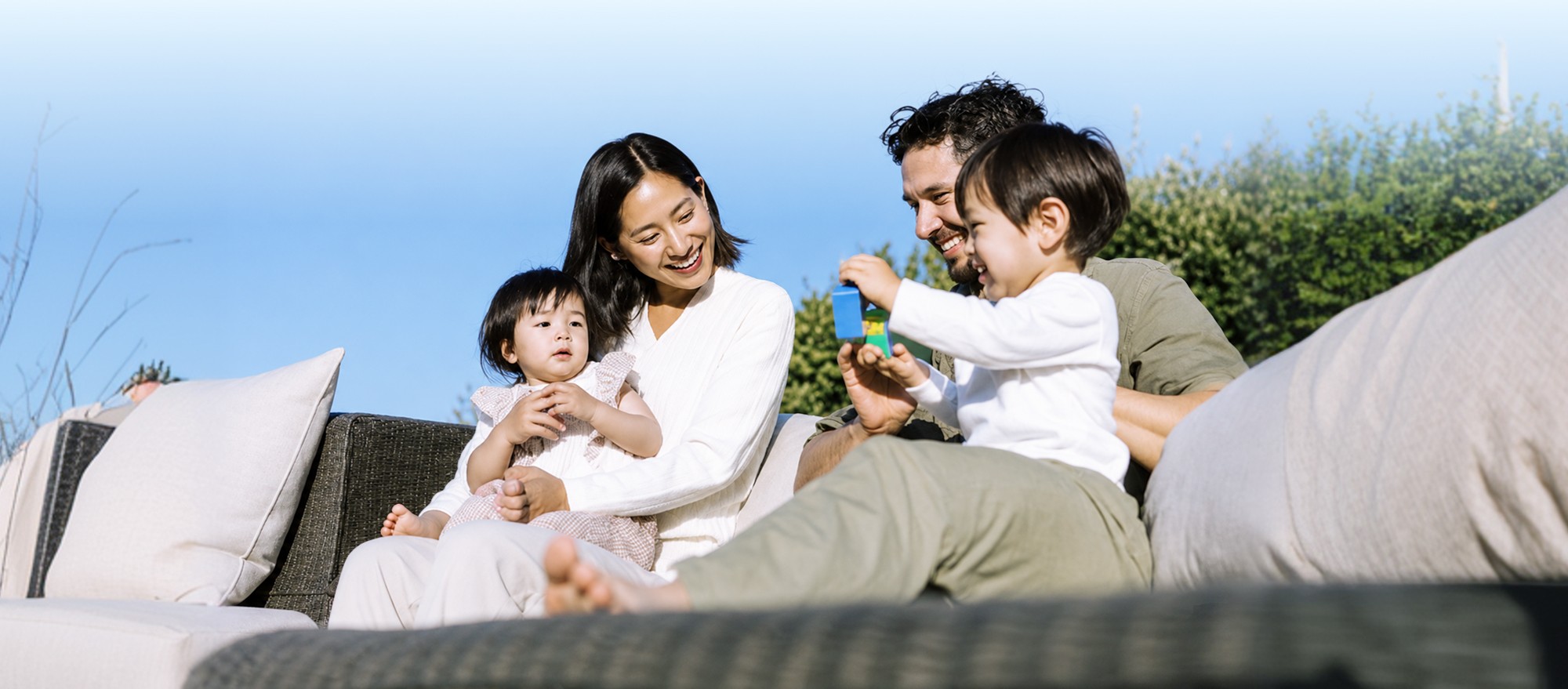 A family plays together with building blocks outdoors.
